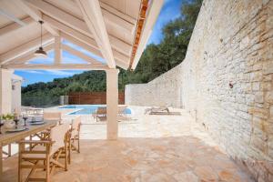 a patio with a table and chairs and a stone wall at Villa TheView in Katávolos