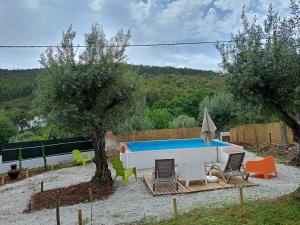 een achtertuin met een zwembad en stoelen en een boom bij Moinho de Palma de NaturAlegre in Alegrete