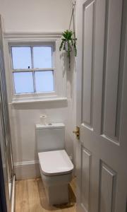 a white bathroom with a toilet and a window at Studio apartment - The Sapphire 
