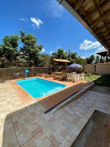 a swimming pool with chairs and a table and an umbrella at Casa das orquídeas in Santana do Riacho