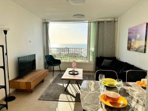 - un salon avec un canapé, une table et une télévision dans l'établissement Sea Breeze Apartment, à Qiryat Yam