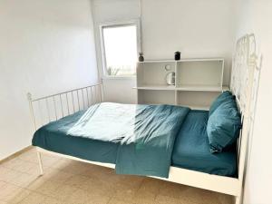 Qiryat YamにあるSea Breeze Apartmentの白いベッド(青いシーツ付)が備わるベッドルームです。