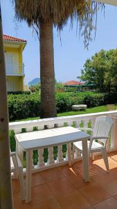 a white bench and two chairs on a patio at Bonisis Studios in Laganas