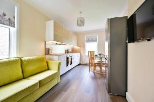 a living room with a green couch and a kitchen at Greenwich Holiday Home in London