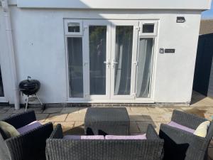a patio with chairs and tables in front of a door at Porthkidney Suite, Carbis Bay, St Ives, free parking, near beach in Carbis Bay