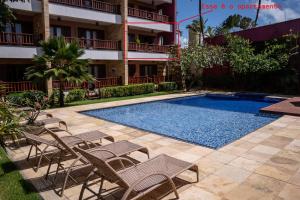 een resort met een zwembad en stoelen en een gebouw bij Apartamento de Charme no Cumbuco - Condomínio Jardim Reale in Caucaia