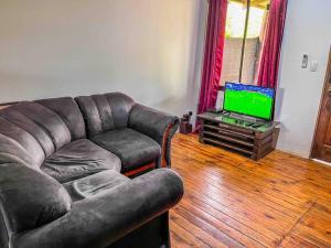 uma sala de estar com um sofá e uma televisão em Cabaña D&E en Copal KiteBeach em La Cruz