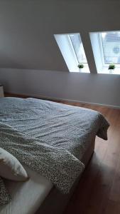 a bed in a bedroom with two windows at Neubau Ferienwohnung - Wallsbüll in Wallsbüll