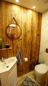 bagno con parete in legno, lavandino e specchio di Mīļpirtiņa Guguči a Straupe
