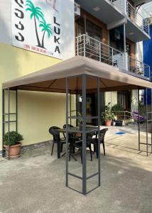 a table and chairs under an umbrella in front of a building at Hotel Luka in Ureki
