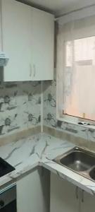 a white kitchen with a sink and a window at Juan in Carlet