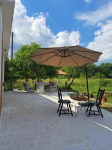 una mesa y sillas con una sombrilla en el patio en Guest house Green River, en Ljubuški