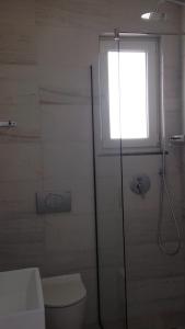 baño con ducha y aseo y ventana en DIELL HOTEL, en Durrës