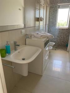 a white bathroom with a sink and a shower at Casalura in Polignano a Mare +10 photos