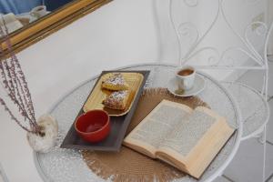 una mesa con un libro y un plato de comida y una taza de café en Casetta nel centro storico, en Mattinata