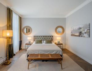 a bedroom with a large bed with two tables and two mirrors at Roosevelt Stadthaus in Vienna