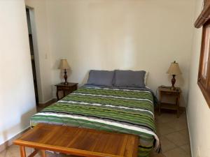 een kleine slaapkamer met een bed en een houten tafel bij Ritz Empress in San Juan del Sur