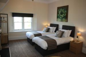a hotel room with two beds and a window at The Rectory Lacock - Boutique Bed and Breakfast in Lacock