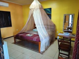 a bedroom with a bed with a mosquito net at Pousada Estrela Feliz in Canavieiras