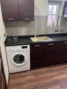 a kitchen with a washing machine and a sink at Unique Studio Flat in City Center in Leicester