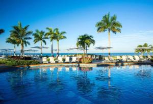 a swimming pool with chairs and palm trees and the ocean at Kingdon of the Sun in Nuevo Vallarta 
