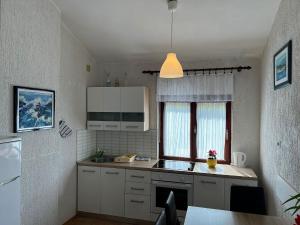a small kitchen with white cabinets and a window at Apartments Dora and Tonka Krk in Porat