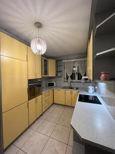 a large kitchen with yellow cabinets and a ceiling at Stan na dan Jakov in Ljubuški
