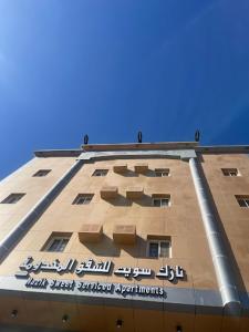 um edifício alto com uma placa na lateral em Nazik sweet - نازك سويت شقق فندقية em Tabuk
