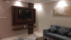 uma sala de estar com um sofá e uma televisão de ecrã plano em Nazik sweet - نازك سويت شقق فندقية em Tabuk
