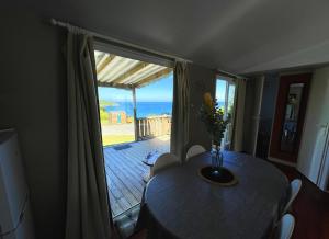 a dining room with a table and a view of the ocean at Bungalow Breizh Vue in Plouha