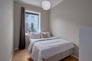 Schlafzimmer mit einem Bett mit weißer Bettwäsche und einem Fenster in der Unterkunft Luxurious w/ beautiful location in Bergen