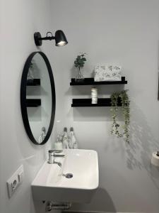La salle de bains blanche est pourvue d'un lavabo et d'un miroir. dans l'établissement Apartamento Turístico Damajuana, à Espartinas