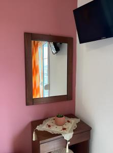 uno specchio su una parete rosa accanto a un tavolo di Chrysa Rooms a Leptokarya