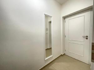 een witte hal met een deur en een spiegel bij Washingtonova apartment 006 in Praag