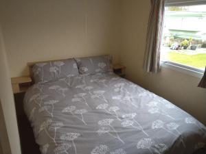 a bed with a gray comforter and a window at Caravan for hire in Lancaster