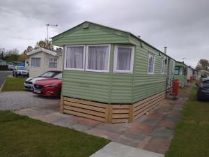 a green tiny house parked in a driveway at Caravan for hire in Lancaster