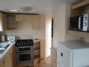 a small kitchen with a stove and a microwave at Caravan for hire in Lancaster