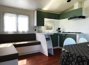 a small kitchen with green cabinets and a table at Bungalow Breizh Vue in Plouha