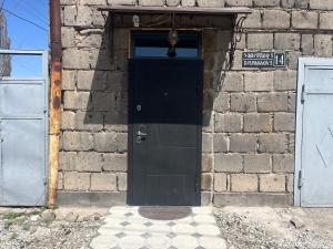 uma porta preta num edifício de tijolos com um sinal em Տուն-Տեղ Tun-Tegh em Guiumri