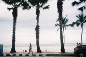 a man walks past palm trees on the beach at Cozy&Beach House-2BRs, Beach, Walking St, Pier in Pattaya South