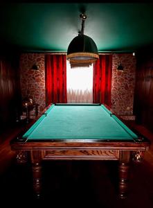 uma mesa de bilhar num quarto com uma cortina vermelha em DOM GOŚCINNY NAD JEZIOREM BIAŁYM em Gorzewo