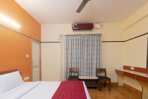 a bedroom with a bed and a desk and a television at Hotel Telehaus International in Bangalore