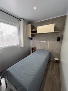 ein kleines Schlafzimmer mit einem Bett und einem Fenster in der Unterkunft Bondi Beach in Renesse