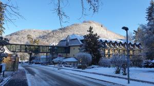 a building on a snowy street with a mountain in the background at Bergzauber Apartment mit Pool, Sauna, Balkon und Panoramablick in Bad Harzburg