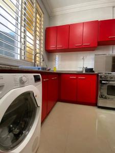 a kitchen with red cabinets and a washing machine at Spacious 2 Bedroom House East Legon Accra in Accra