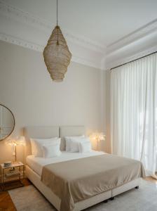 ein weißes Schlafzimmer mit einem großen Bett und einem Kronleuchter in der Unterkunft Roosevelt Stadthaus in Wien
