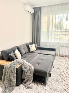 een woonkamer met een grijze bank en een raam bij - Cozy Apartment in Quite Area - in Tasjkent