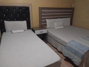two beds in a hotel room with two beds at M-Dee Guest Pass Lodge in Phuthaditjhaba