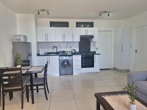 a kitchen with white cabinets and a table and chairs at City Junction Windhoek in Windhoek