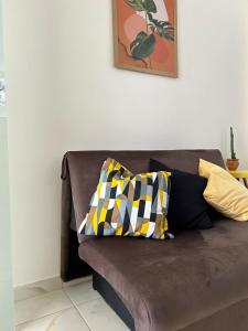 Un sofá marrón con dos almohadas coloridas. en Apart Recanto da Floresta en Camaçari